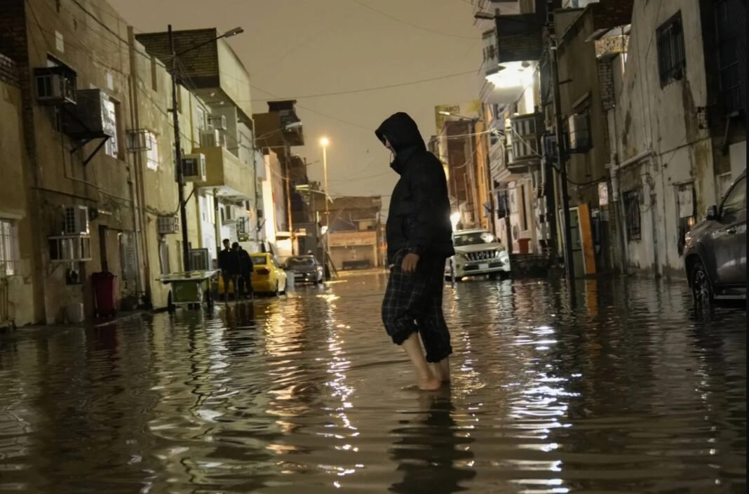 عراقي يخوض في مياه أمطار أغرقت شوارع العاصمة بغداد في 7 مارس 2025